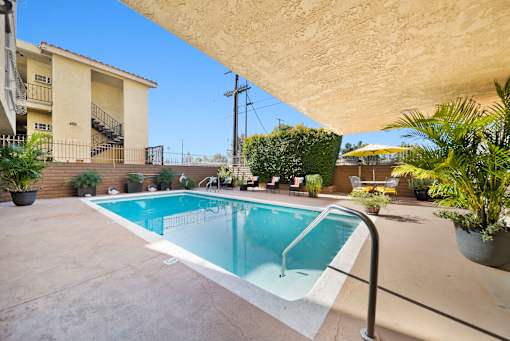 A small pool in a backyard with a building in the background.