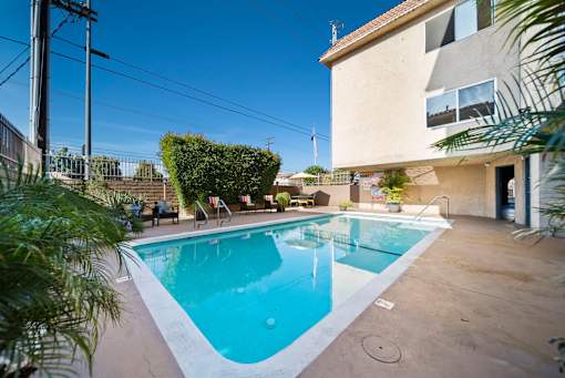 A small pool in a backyard with a house in the background.