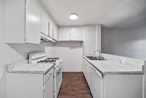 A kitchen with white cabinets and a marble countertop.