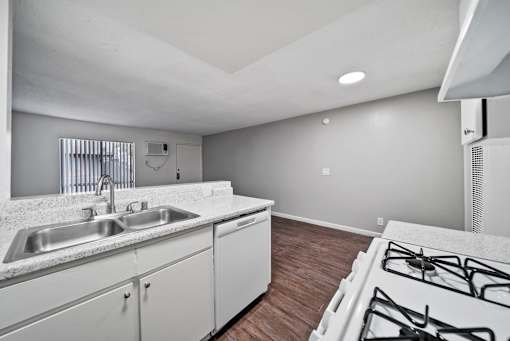 A kitchen with a stove, sink, and cabinets.