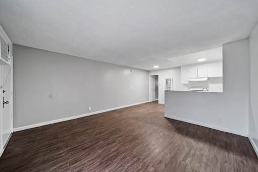 A large empty room with wood flooring and white walls.