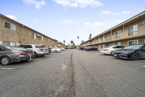 A parking lot with cars parked in front of apartment buildings.