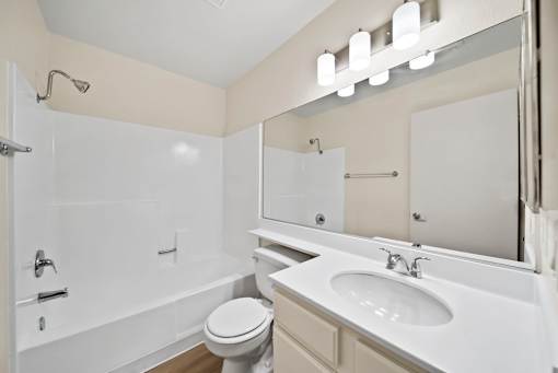 A white bathroom with a toilet, sink, and bathtub.