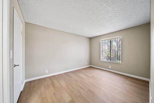 A room with wooden flooring and a window with blinds.