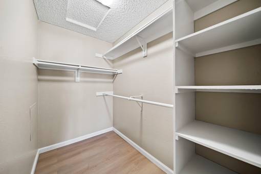 Empty walk-in closet with shelves and a white ceiling.