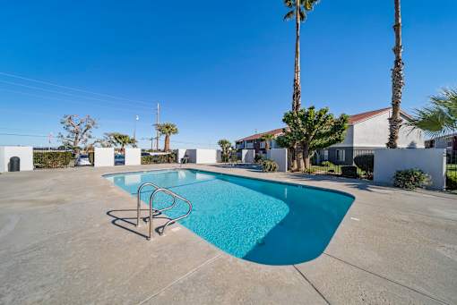 A swimming pool surrounded by palm trees and buildings.