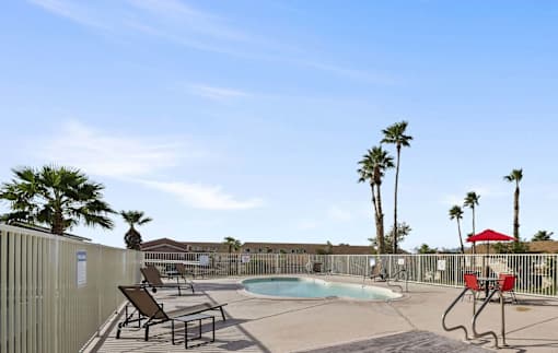 A pool area with sun loungers and palm trees.