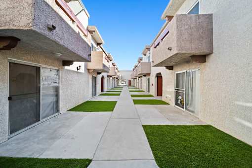 A long concrete walkway separates apartment buildings.