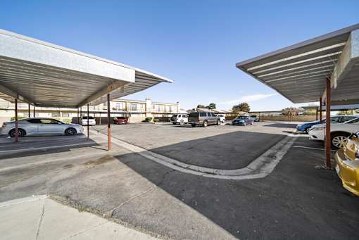 A parking lot with cars parked under a metal roof.