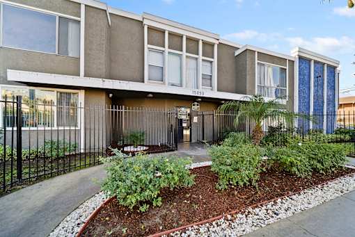 A modern building with a front garden and a black fence.