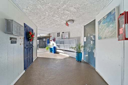 A hallway with a blue trash can and a red fire extinguisher on the wall.