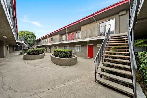 A courtyard with a red door and a staircase.