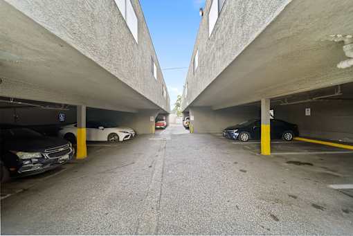 A parking garage with cars parked on both sides of the aisle.