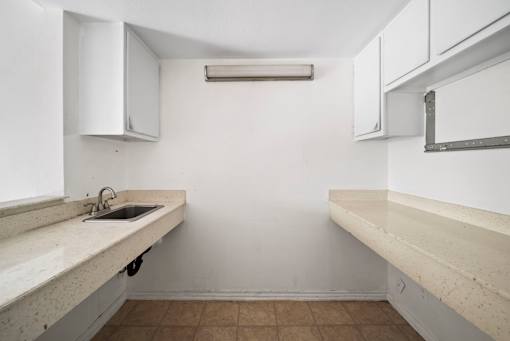 A kitchen with white cabinets and a brown floor.