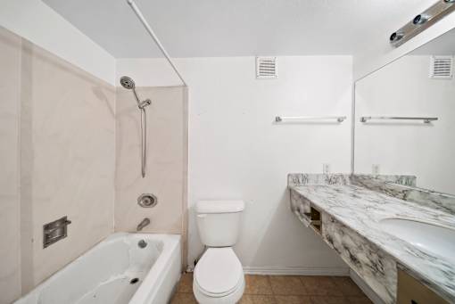 A white toilet sits next to a bathtub in a bathroom.