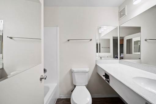 A white bathroom with a toilet, sink, and mirror.