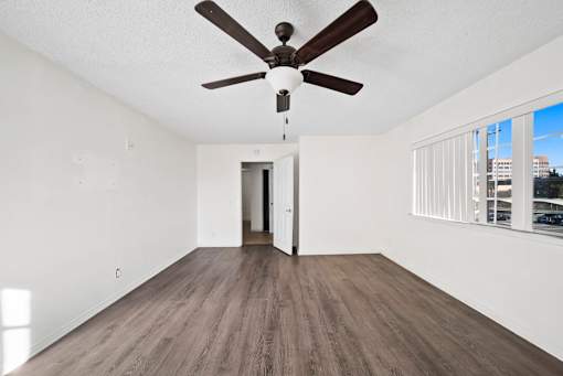 A room with a ceiling fan and wooden flooring.
