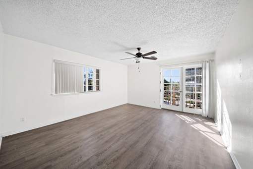 A room with a ceiling fan and a sliding glass door leading to a balcony.