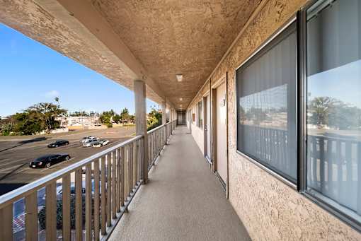A long balcony with a concrete ceiling and a metal railing.
