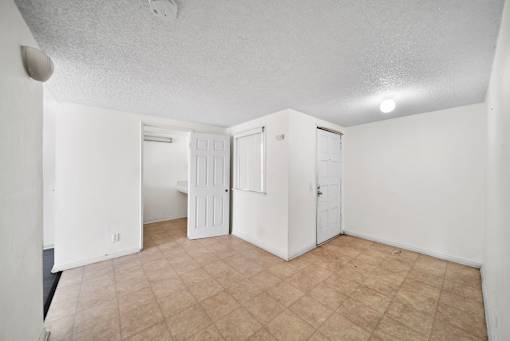 A room with white walls and a beige tile floor.