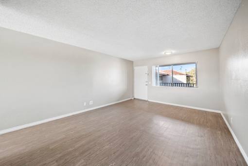Empty room with wooden flooring and a window.