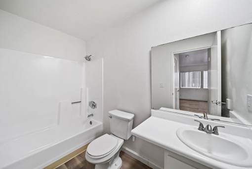 A white bathroom with a toilet, sink, and bathtub.
