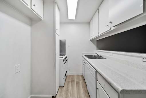 A kitchen with white cabinets and a black counter top.