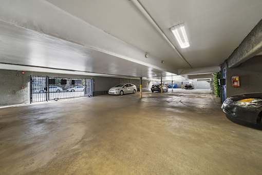 A parking garage with a white car and a black car parked inside.