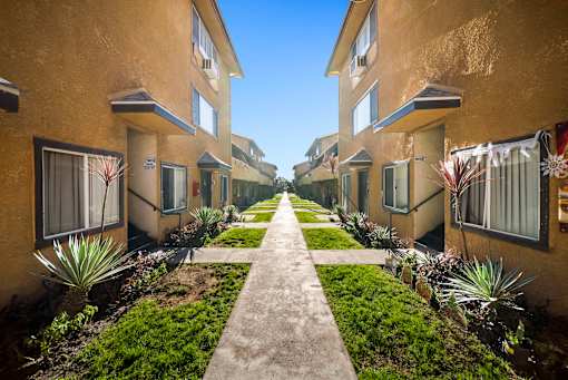A row of houses with a concrete walkway between them.