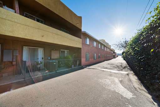 A sunny day in a quiet residential street with apartment buildings on either side.
