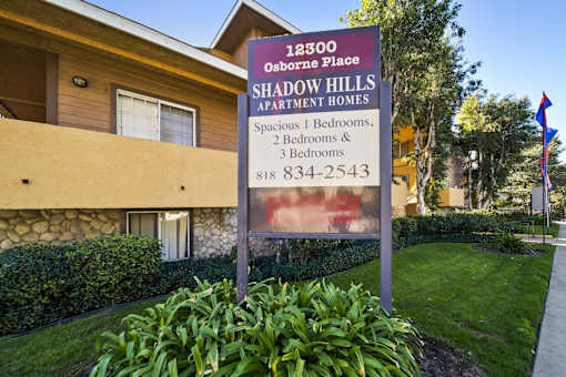 A sign for Shadow Hills Apartment Homes is in front of a building.