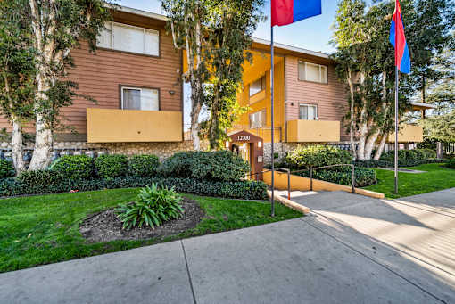 A building with a brown and yellow exterior and a small garden in front.