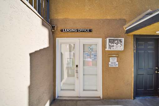 A leasing office is located in a building with a white door and a sign above it.