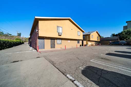 A yellow building with a grey parking lot in front.