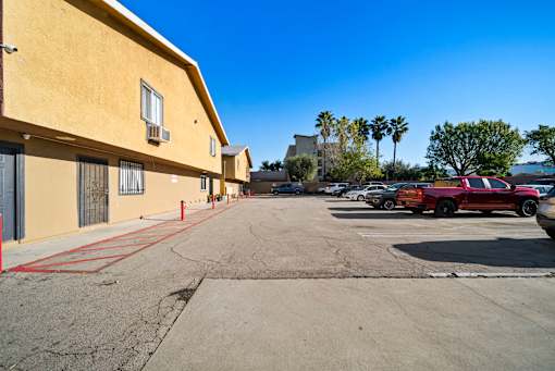 A parking lot with a red car and a yellow building.