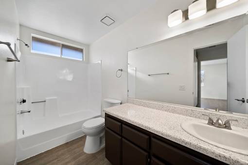 A white bathroom with a toilet, sink, and mirror.