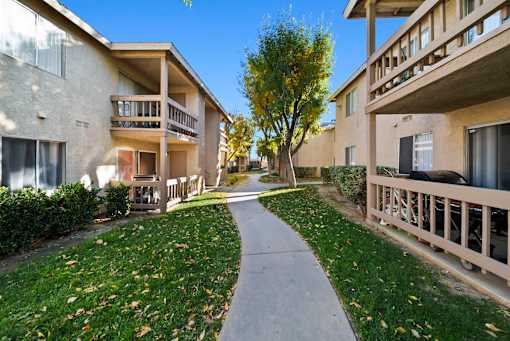 A pathway leads between two buildings with balconies.