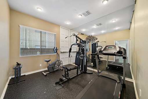 A well-equipped home gym with a treadmill, elliptical trainer, and other exercise machines.