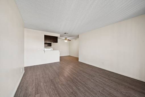 A room with a ceiling fan and a small kitchenette.