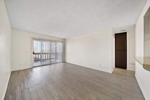A room with a wooden floor and a window with blinds.