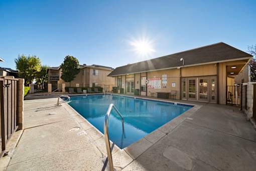 A sunny day at the pool with a building in the background.