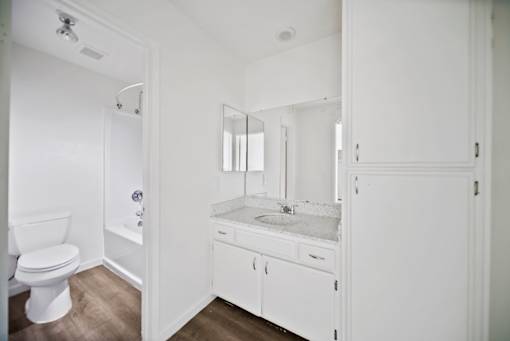 A white bathroom with a toilet, sink, and mirror.