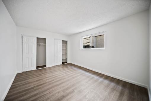 Empty room with a window and wooden flooring.