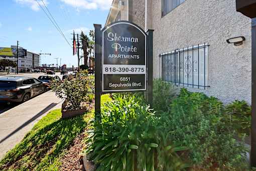 A sign for Sherman Pointe Apartments is in front of a building.