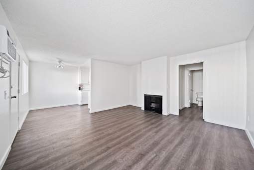 A large, empty room with a fireplace and wood flooring.