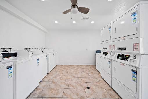A room with a white ceiling and floor, containing a row of washing machines.