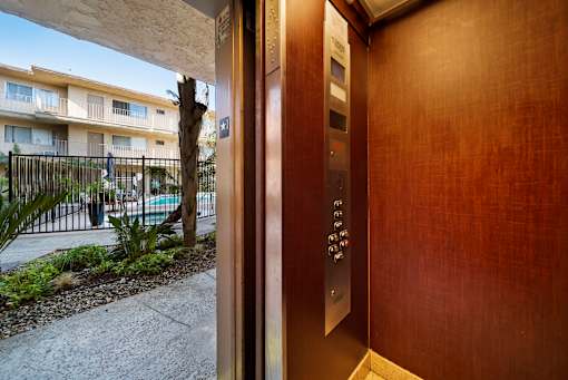 A modern elevator with a wooden panel and a metal handrail.