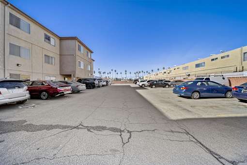 A parking lot with several cars and apartment buildings in the background.