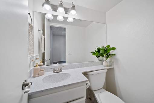 A white bathroom with a sink, toilet, and mirror.