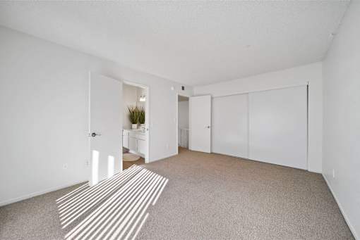 A room with a striped rug on the floor and a doorway leading to another room.